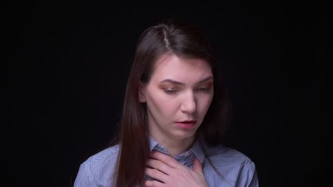 Brunette businesswoman in blue blouse coughing suffering from severe sore throatat black background.