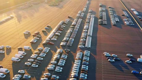 Aerial view of the dealership terminal parking lot with a rows of new cars at sunset