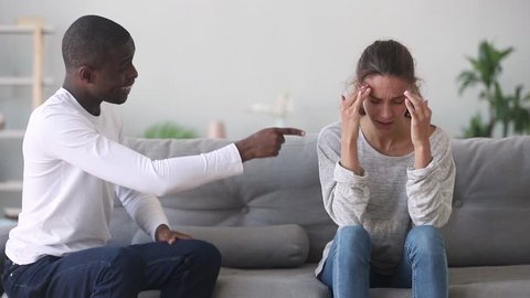 Abusive controlling african american husband shouting at upset caucasian wife, jealous black boyfriend tyrant despot yell at sad stressed girlfriend, mixed ethnicity unhappy couple arguing fighting