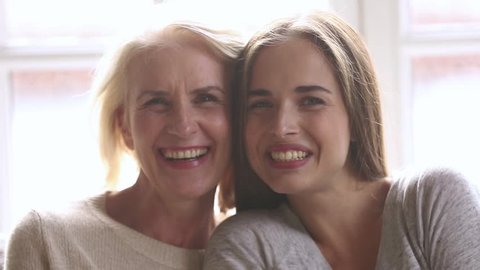Happy beautiful loving family old mature mother and adult daughter laughing bonding looking at camera, smiling senior mom with young woman having fun enjoy connection and warm relationships, portrait