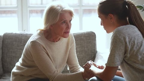 Serious old mother and young daughter having trust conversation talking sharing problems giving advice care support, loving senior mom holding hands of adult woman comforting helping overcome problem