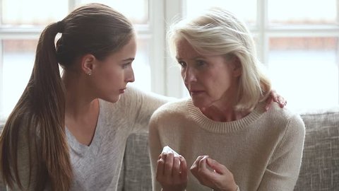 Loving young adult daughter consoling talking to sad crying old senior mother in tears comforting embracing upset older mature woman in tears help parent with problem give support care to elderly mom