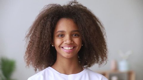 Pretty african american teen school girl looking at camera, adolescent funny mixed race teenage model with afro hair and beautiful face toothy smile posing at home, happy black teenager, portrait