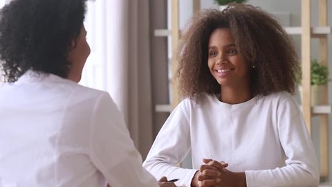 Smiling african american teenage girl listening to female doctor pediatrician school psychologist counselor talk to teen patient at checkup therapy consultation, pediatrist consulting black teenager