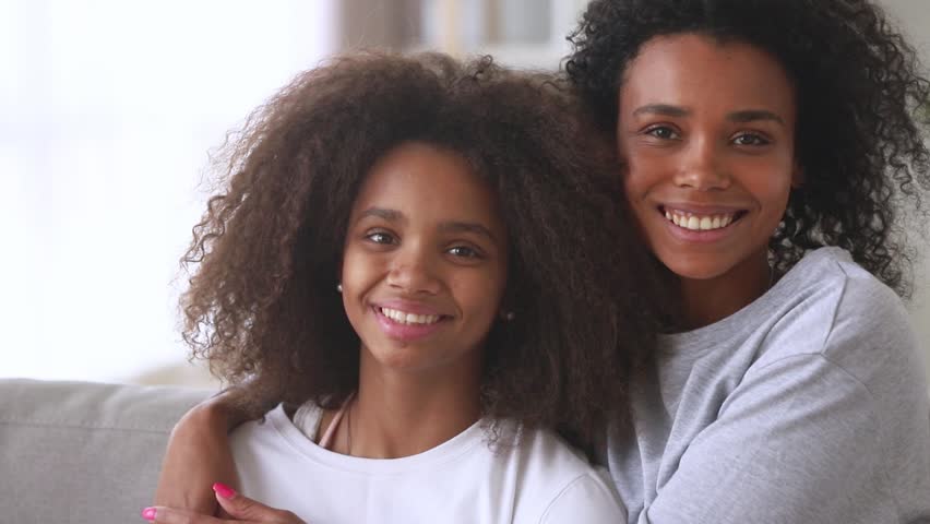 Happy african american family mom with teen daughter hugging laughing looking at camera, cheerful black mother embracing child teenage girl cuddling having fun feeling love and bonding, portrait Royalty-Free Stock Footage #1027488590