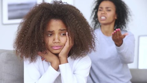 Sad teen african american girl upset by strict mum arguing scolding daughter, stressed stubborn teenager turned back ignoring angry black mother lecturing difficult kid, parent and children conflicts
