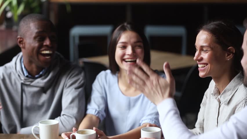 Diverse young happy friends join hands giving high five together celebrating multicultural friendship at reunion cafe meeting, multiracial mates students team bonding engaged in unity support concept Royalty-Free Stock Footage #1027488614