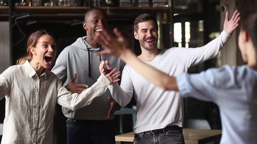 Excited multiracial friends greeting hugging female mate at reunion in cafe, happy diverse young students group embracing say hello welcome girl coming at meeting, multicultural friendship concept Royalty-Free Stock Footage #1027488632