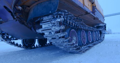 Tracked all-terrain vehicle in the far north, in the harsh low temperatures begins to drive on the territory of the oil and gas complex. Caterpillar and rollers close up