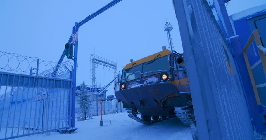 Tracked off-road vehicle with a team of geologists in the far north, in the harsh low-temperature conditions, leaves the territory of oil and gas complex 
