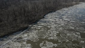 Slow panning aerial shot over river with ice flows looking at a cold forest. Filmed with a Mavic 2 Pro, 4K footage at high bit rate.