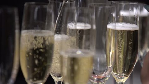 On the table are empty glasses and glasses of champagne,the bartender/waiter fills the empty glasses of champagne, close-upの動画素材