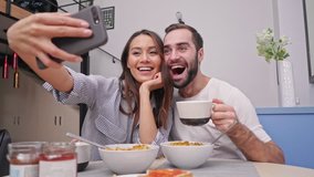 Happy lovely couple having breakfast while sitting together on kitchen