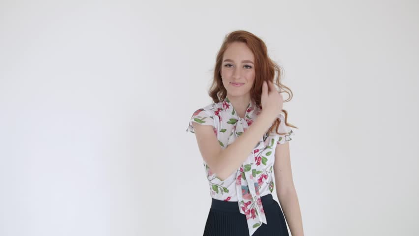 Sexy girl with red hair posing on white background touching her hair