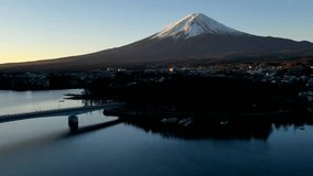HD time lapse video of Mt Fuji in Japan with lake, water and bridge in the foreground and the snowy mountain of Mt Fuji in the background along with clear blue skies.