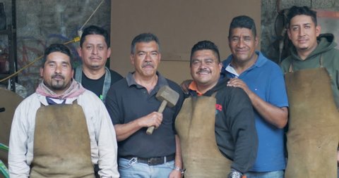 Portraits of six friendly smiling Mexican men looking at the camera in their workshop