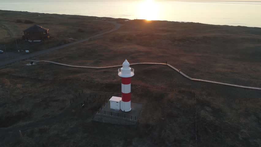 Taken with a drone advancing towards the sea from right above the lighthouse at dusk
