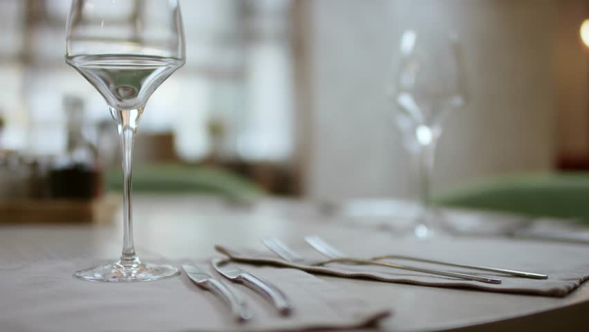 The waiter serves the table in the cafe. Video from the restaurant. The waiter straightens the knife on the table. Table setting. Preparing the restaurant for the opening. decorated table for a dinner | Shutterstock HD Video #1027516739