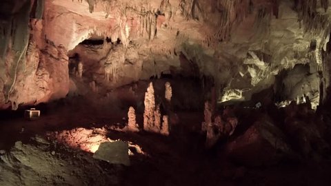smooth shooting of mysterious stone cave of Prometheus in Georgia, enchanting beauty of wildlife, stalactites and stalagmites illuminated with bright lamps, movement along river through mountain