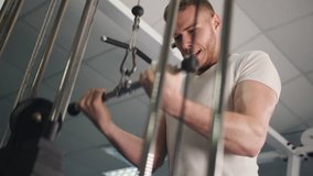 Male training arms triceps muscles using cable machine for body mass. Man in gym doing weight exercise 4k video. Workout bodybuilding sport concept