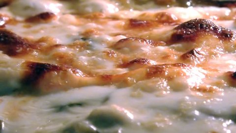 baking Moussaka with vegetables and bechamel boiling in a oven. Close up view of cheese bubbles. Traditional greek dish.