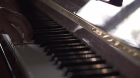 Musician plays piano, in Slow Motion video, in a room with natural light