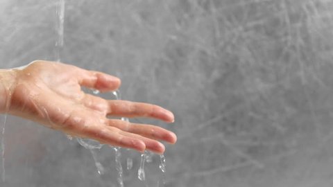 Water is pouring through the man's hand. Time concept. Hand close-up.