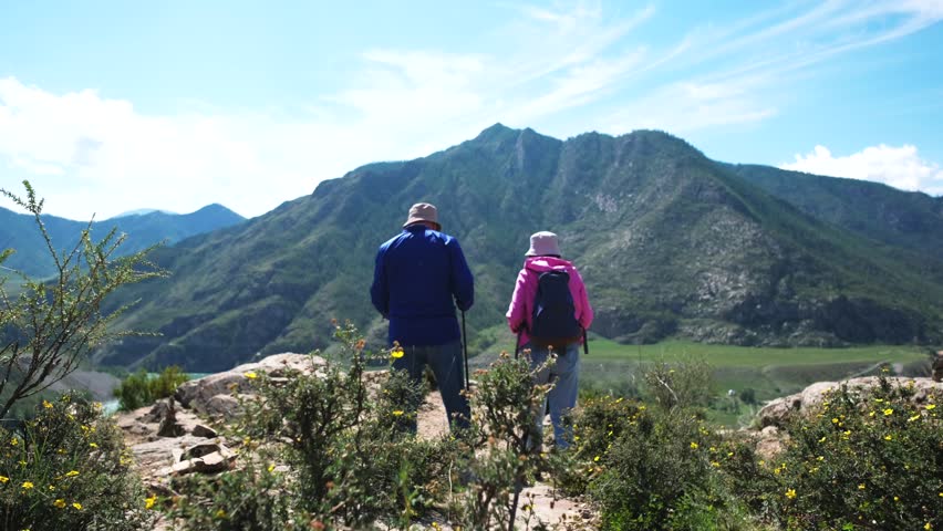 Two elderly tourists admire the view of the river and mountains from a height