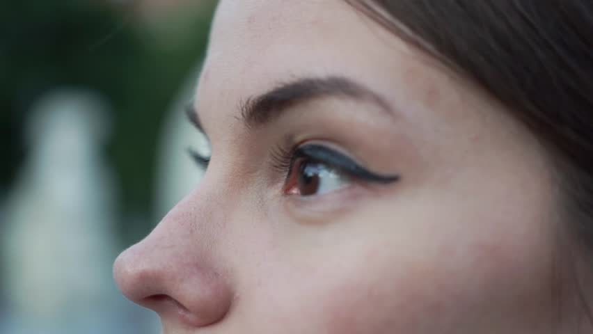 Close-up of woman with broun eyes and freckles looking at view in summer