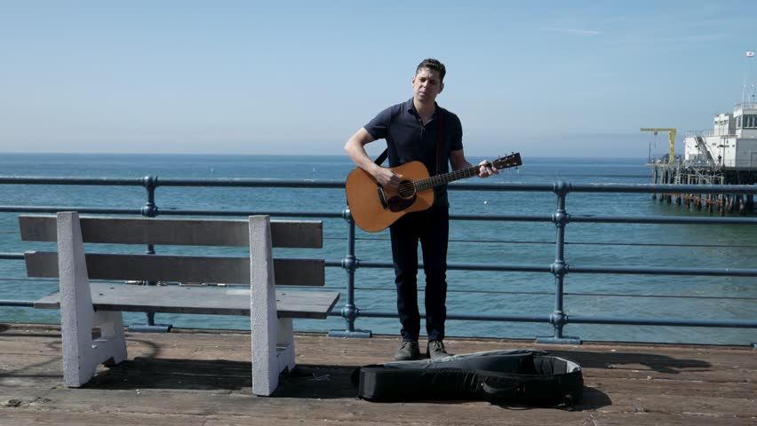 Street performer gives up for the day and packs up his guitar.