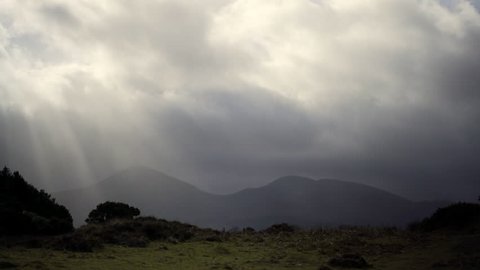 Irish mountain range with rolling clouds and sun rays breaking through in Mourne country, ideal walking trip.