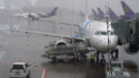 Storm at the airport. View of the airplane through rain drops and streams. Themes of weather and delay or canceled flight.