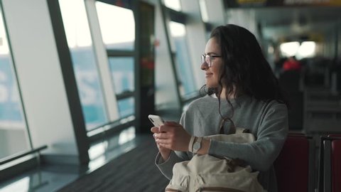 girl uses smartphone in the airport lounge.