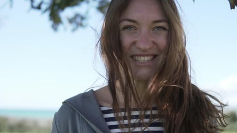 Beautiful young woman on vacation at sea. Close-up of a happy female face without makeup. She is walking in the park