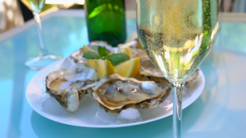 Fresh tasty oysters lie in a plate with ice on a table with wine outdoors.