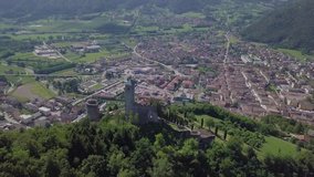 Aerial panoramic view of Borgo Valsugana in Trentino Italy with views of the city and mountains with drone flying behind Castel Telvana
