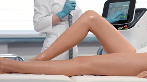 Medium shot of patient's legs during laser hair removal procedure. Slow motion. | Unwanted hair and laser hair removal concept.