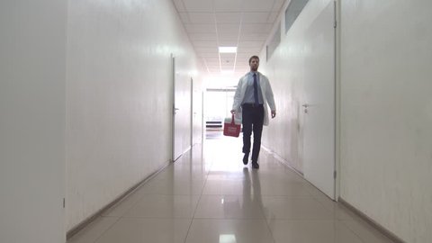 Medical courier delivers human organ for transplant | Man in white coat with red organ trafficking container in his hand going down the corridor at the hospital