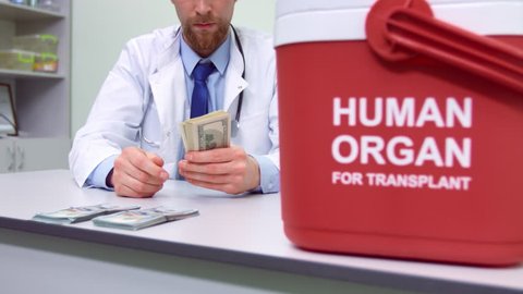 Male doctor in white coat sitting in his office and counting ready money at the background of organ trafficking container | Illegal human organ trade concept.