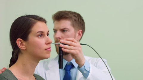 Male otolaryngologist examining female patient with endoscope | Ear examination