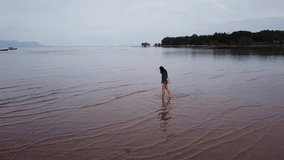 Girl walking in shallow waters on the island of Phu Quoc, Vietnam. Drone Moving low altitude aerial footage. 