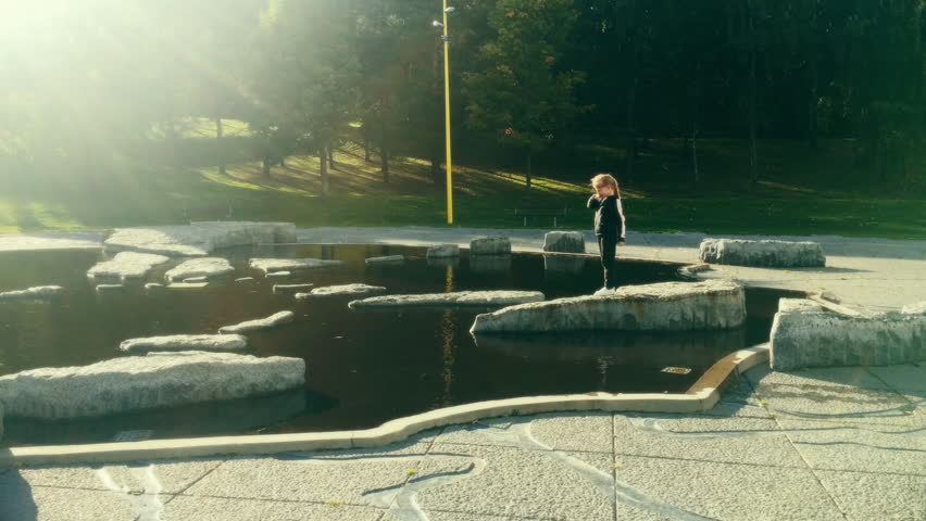 A young girl explores the water at a park, filmed in UHD 4K