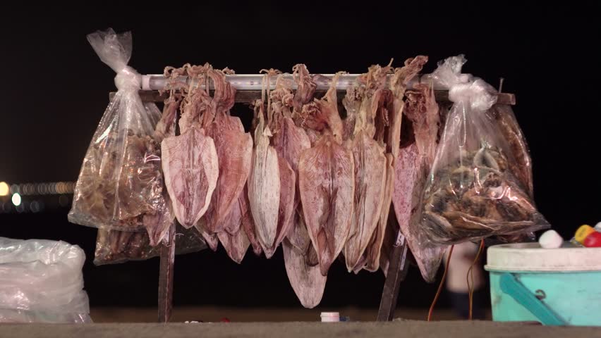 A bunch of squid dries against the night sky.