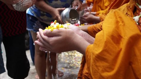 Pouring water with flower into the monk's hand. This is a gesture of worship during the annual Songkran festival.