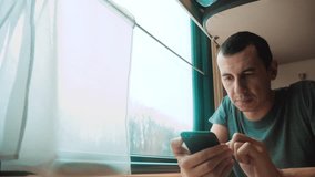 man travel writes smartphone a message social media in the messenger sits on the train by the window traveler concept train railroad journey travel. slow motion video. beautiful from window of a