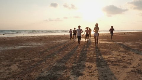 Asian teen group walk and run together at seaside beach summer with sunset background. Young asia happy emotion and anniversary celebration. 4K resolution and slow motion. ஸ்டாக் வீடியோ
