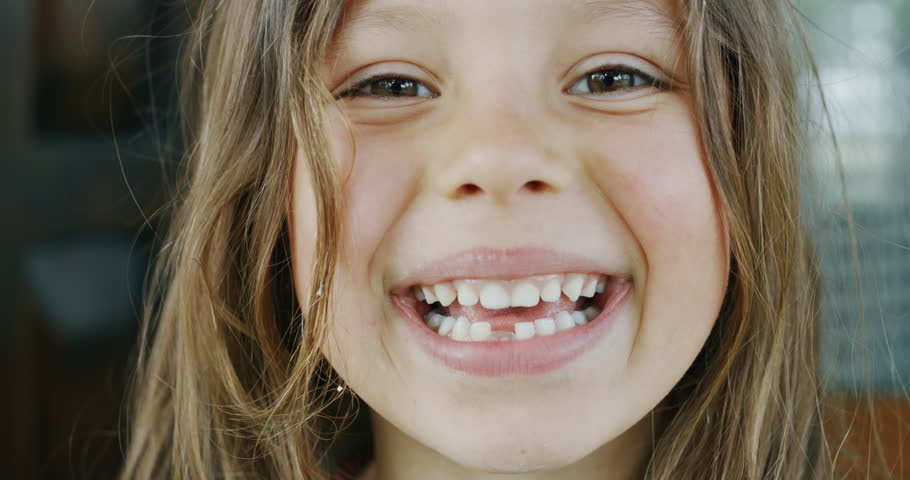 Authentic shot of cute little girl smiling in camera with decayed teeth outside her house on a sunny day. | Shutterstock HD Video #1027622378