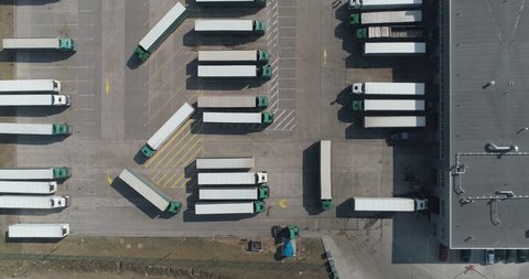 Buildings of logistics center, warehouses near the highway, view from height, a large number of trucks in the parking lot near warehouse.