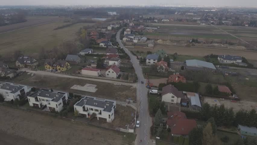 View from the top down to the European village. A small village in the suburbs of Warsaw. Top view over the houses surrounded by green lawns. Drone shot 4k. Video format RAW.