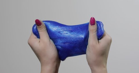 Woman hands playing with oddly satisfying blue slime sticky gooey substance on white background. Super viral trend on social media for those little things that are inexplicably satisfying. Antistress
